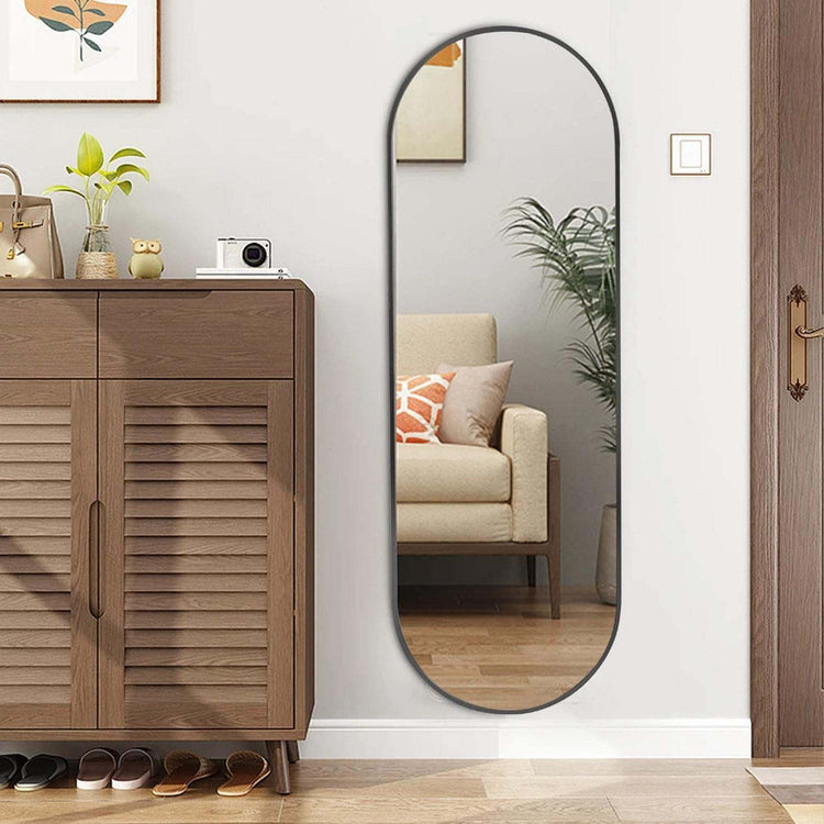 Oversized oval full-length mirror leaning against a wall enhancing room light and space