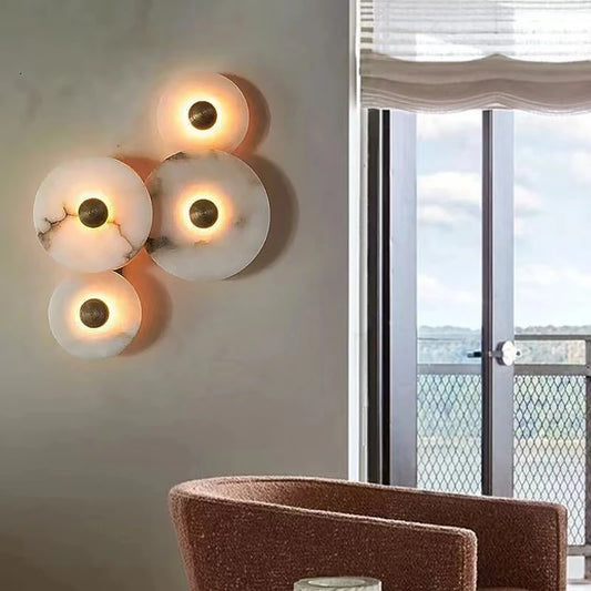 Round marble wall sconce with natural stone texture and soft halo light behind it