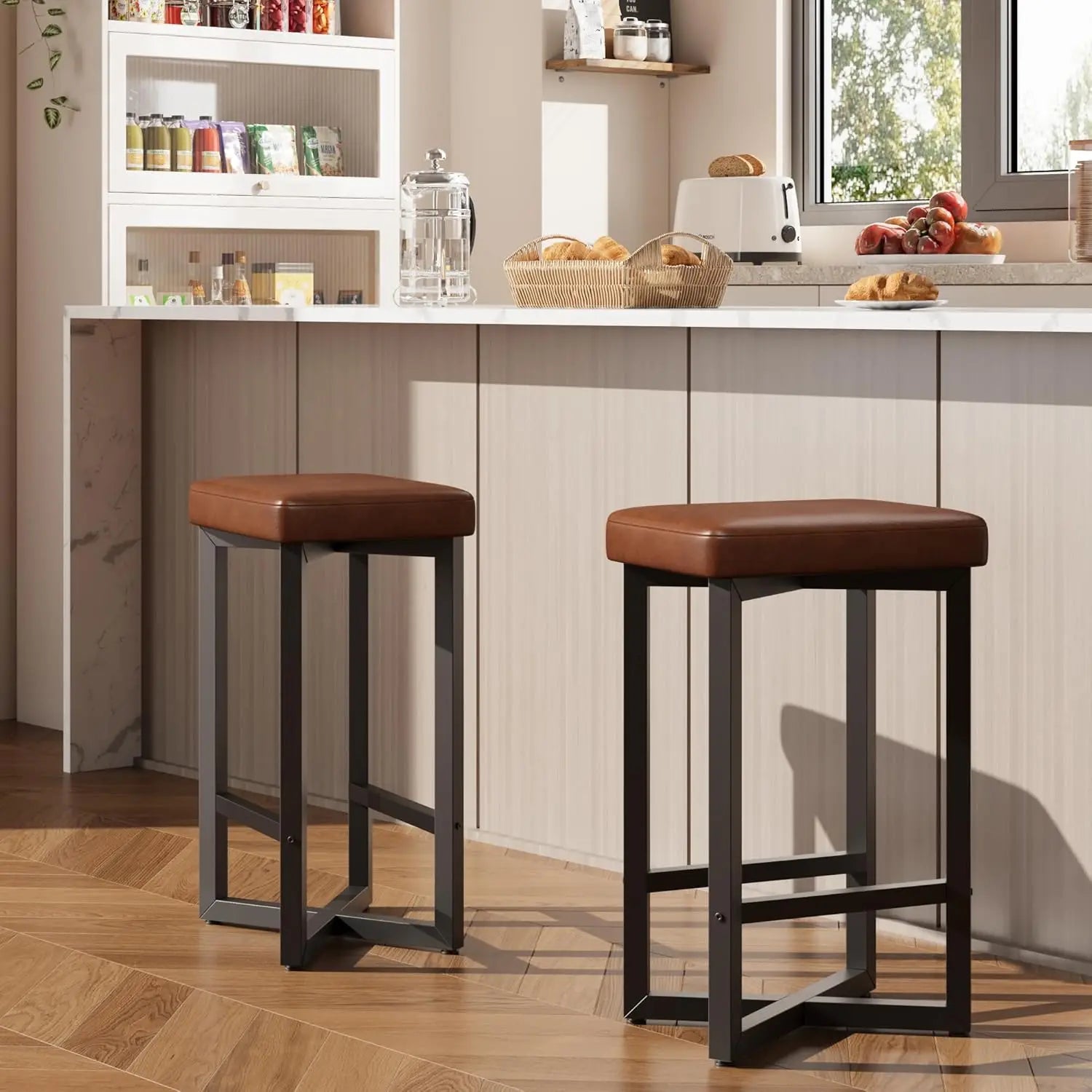 Modern kitchen setting featuring a 24" Bar Stools Set of 2 — Backless Counter Height with PU Leather Seat in brown with black metal legs, offering sleek and minimalist dining furniture.
