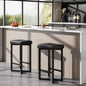 Modern kitchen interior featuring a 24" Bar Stools Set of 2 — Backless Counter Height with PU Leather Seat in black, paired with a light wood breakfast bar and natural sunlight.