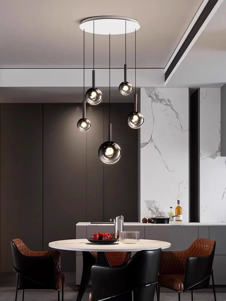Nordic Stair Chandelier — Living & Dining Room Pendant Ceiling Light featuring five modern glass globe pendants suspended at varying heights over a contemporary dining table in a minimalist setting.