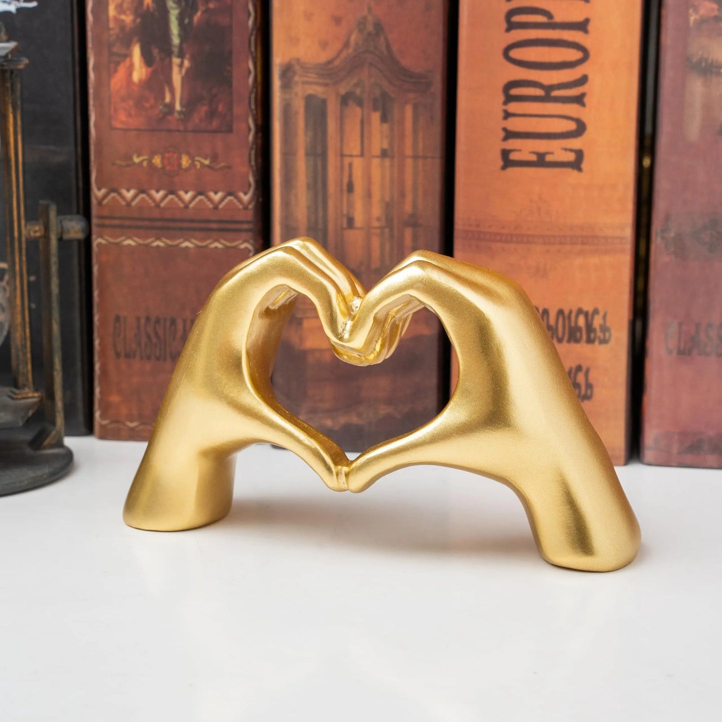 Heart hand love sculpture with gold hands forming a heart on a black base