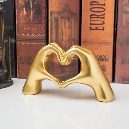 Heart hand love sculpture with gold hands forming a heart on a black base