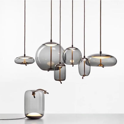 A set of six modern gray glass pendant lights with brass accents and black cords, styled as the Modern LED Pendant Light — Chandelier for Living & Dining Room in a minimalist setting.