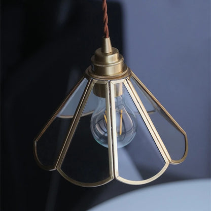 Retro brass pendant light with clear glass globe shade and warm glowing bulb