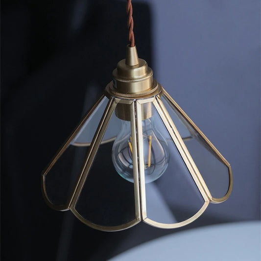Retro brass pendant light with clear glass globe shade and warm glowing bulb