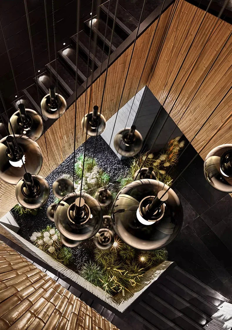 Overhead view of a modern staircase illuminated by the Nordic Stair Chandelier — Living & Dining Room Pendant Ceiling Light with multiple pendant glass spheres, highlighting a vertical garden below.