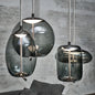 Modern LED Pendant Light — Chandelier for Living & Dining Room with four sculptural smoked glass shades hanging from braided cords against a gray brick wall, showcasing minimalist luxury home décor.