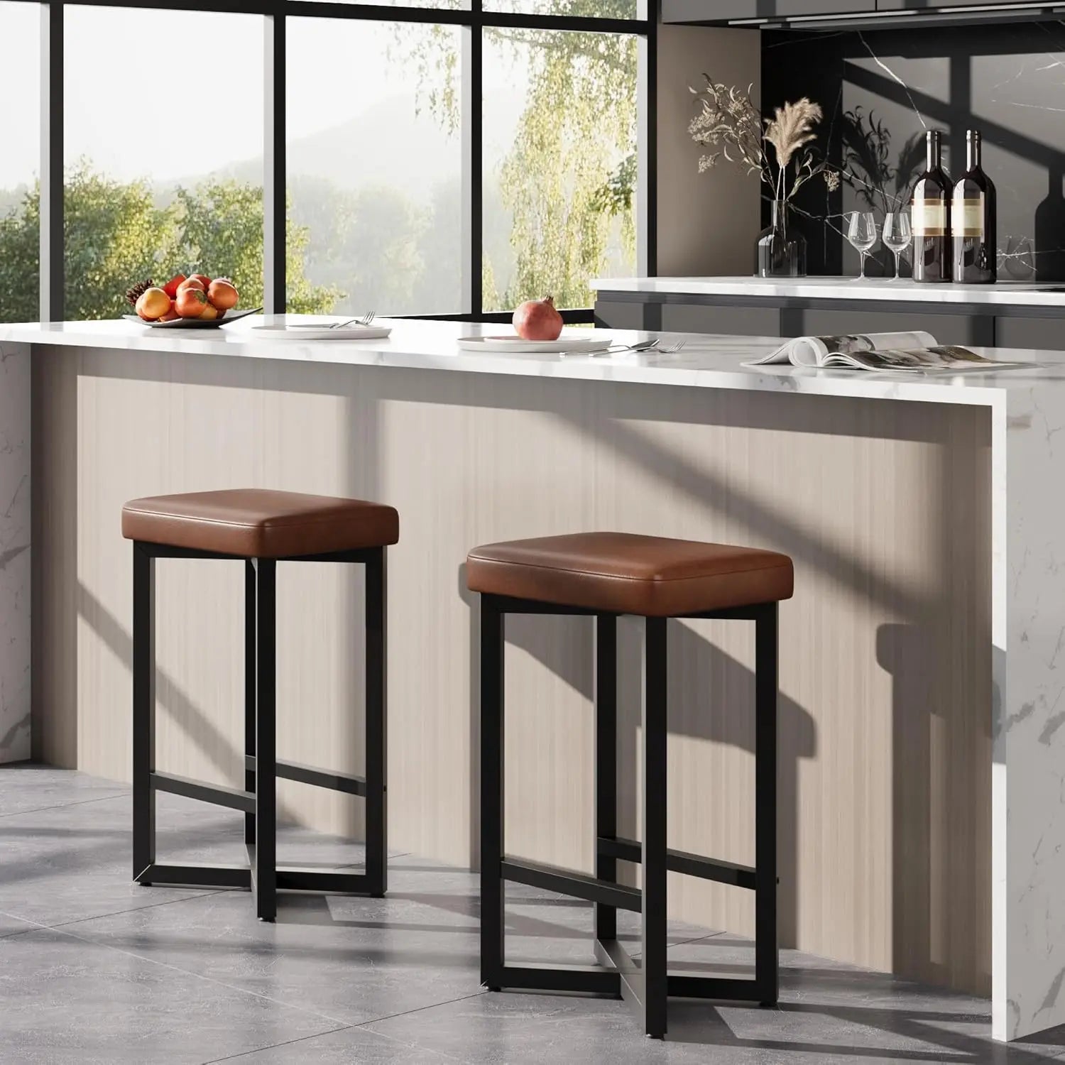 Two modern 24" Bar Stools Set of 2 — Backless Counter Height with PU Leather Seat in brown with black metal legs positioned in a bright kitchen with a marble countertop and large windows.