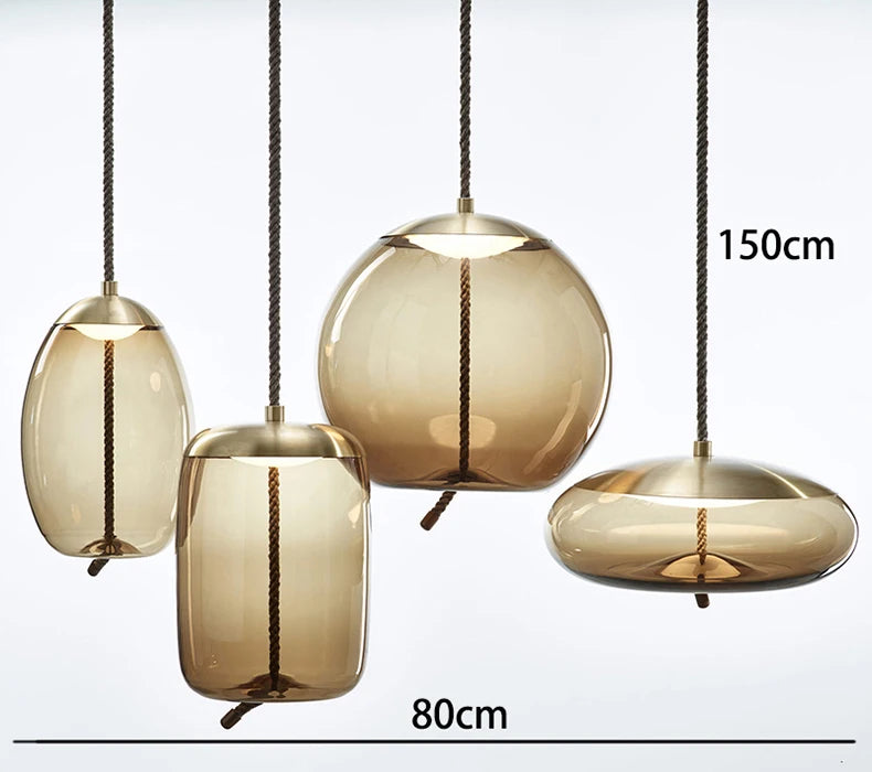 Modern LED Pendant Light — Chandelier for Living & Dining Room featuring four amber glass pendant shades suspended by dark twisted cords, showcasing a Nordic-inspired design.