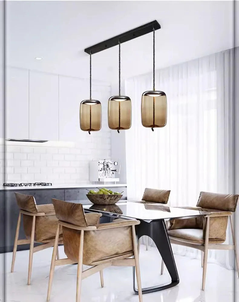 Modern LED Pendant Light — Chandelier for Living & Dining Room hanging above a sleek dining table with brown leather chairs in a bright, minimalist space with white walls and large windows.
