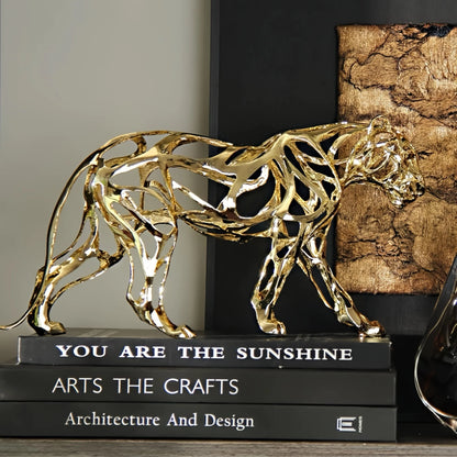 Nordic Metal Leopard Sculpture — Living Room Desktop Home Décor in gold-tone metal with an openwork design, placed atop stacked design books in a modern minimalist setting.