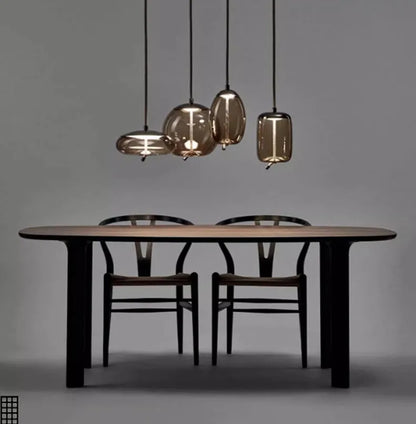 Modern LED Pendant Light — Chandelier for Living & Dining Room featuring four unique smoky glass pendants hanging above a minimalist wooden dining table with two chairs, perfect for luxury home décor.