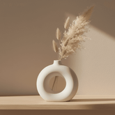 Sleek porcelain doughnut vase with dried pampas on a modern shelf