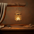 Vintage hanging tealight lantern birdcage casting warm flickering light and intricate shadows